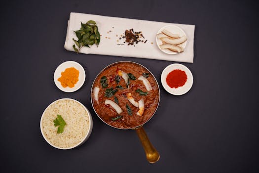 Top view of a traditional Indian curry served with rice and spices on a dark background.