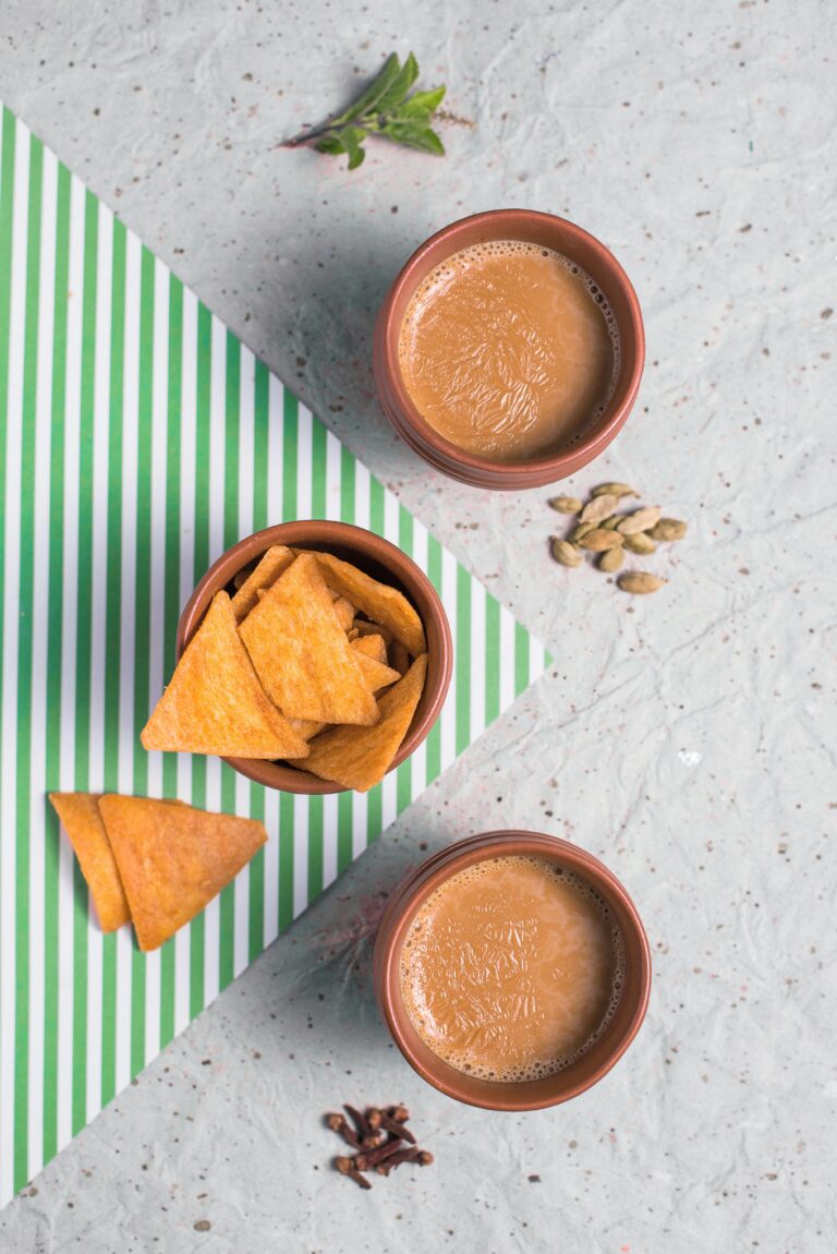 Top view of traditional Indian chai tea with nachos on a striped mat.